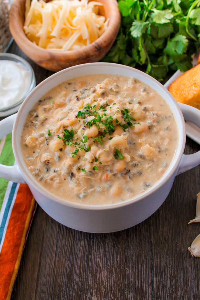 angled shot of creamy hominy and wild rice chili with chicken in a white soup bowl