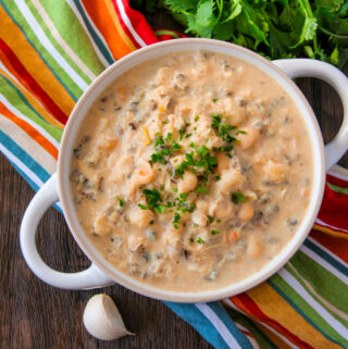 white chicken chili with hominy and white beans in a white bowl on striped napkin