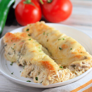 pork enchiladas with green sauce on a white rimmed plate
