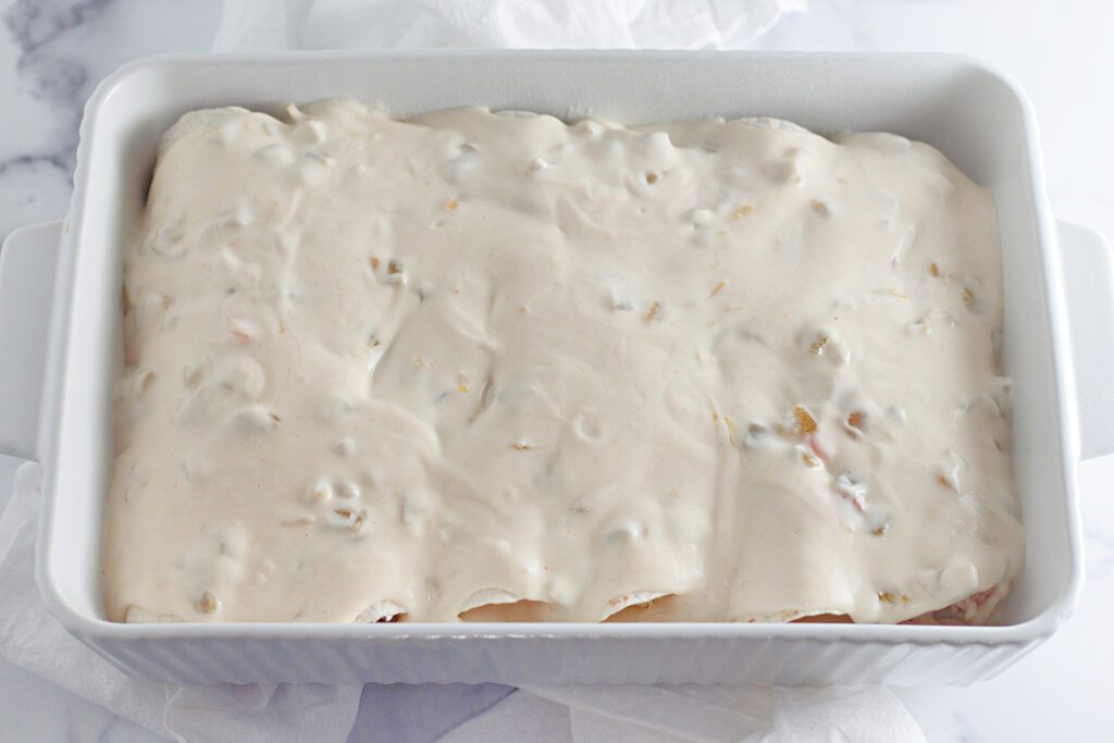 enchiladas coverd with green chiles sour cream sauce, preparing for the oven