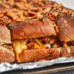 side shot of baked sloppy Joe sliders with Manwich on foil tray