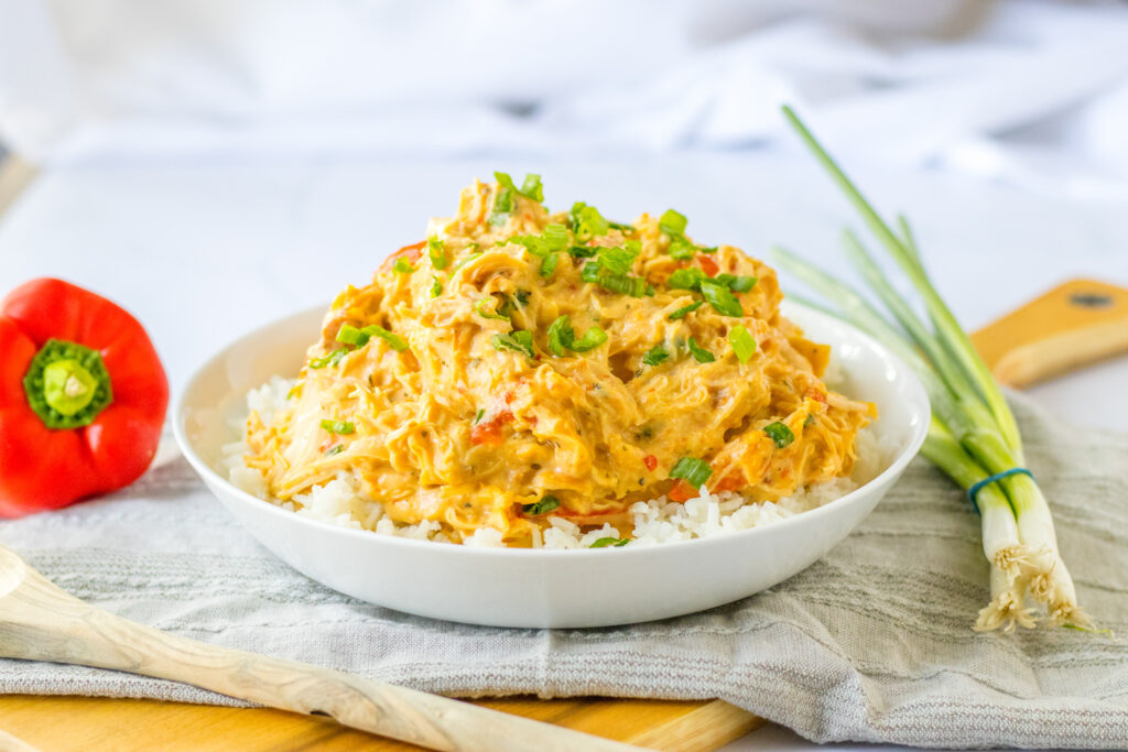 white bowl of slow cooker sweet chili chicken over white rice in white bowl