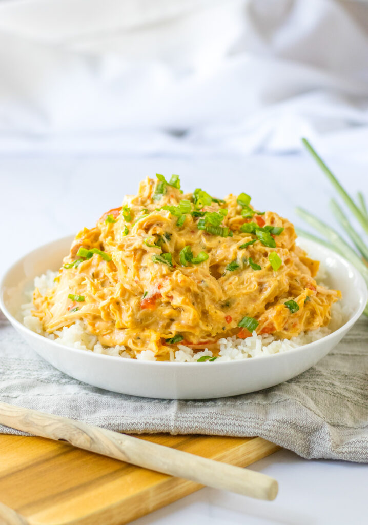 angled side view of slow cooker sweet chili chicken in a white bowl