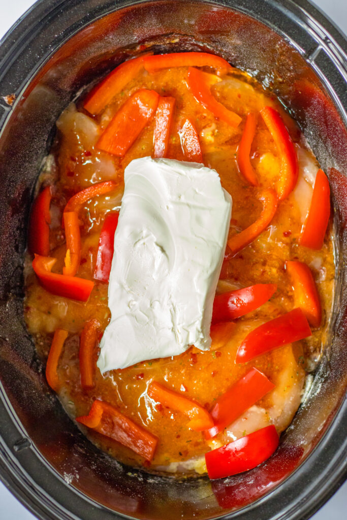 overhead shot of slow cooker sweet chili chicken with cream cheese block on top