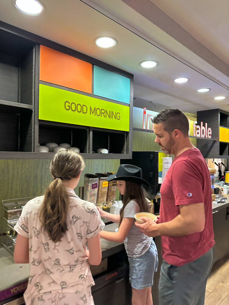 family getting free breakfast in Home2 Suites by Hilton Downtown Nashville lobby