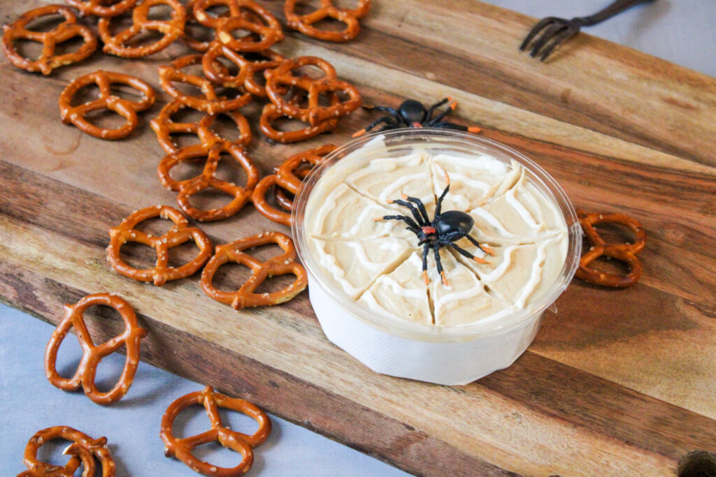 spiderweb Halloween hummus with spiders on top on wooden tray
