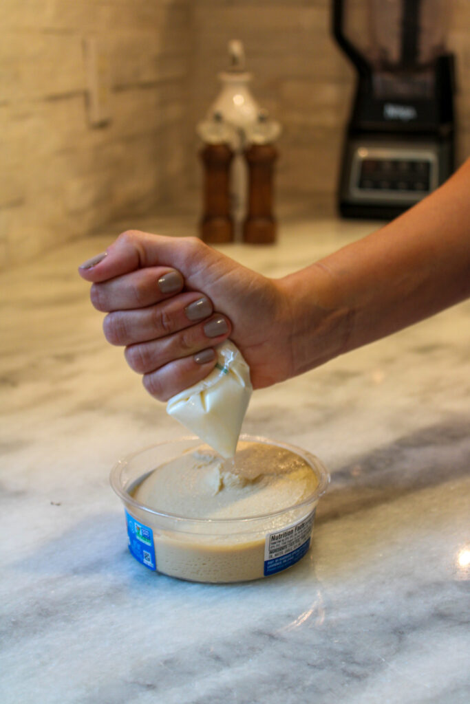 woman squirting sour cream onto a dip