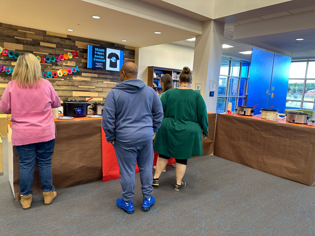 staff members in line at work chili cook off in school library