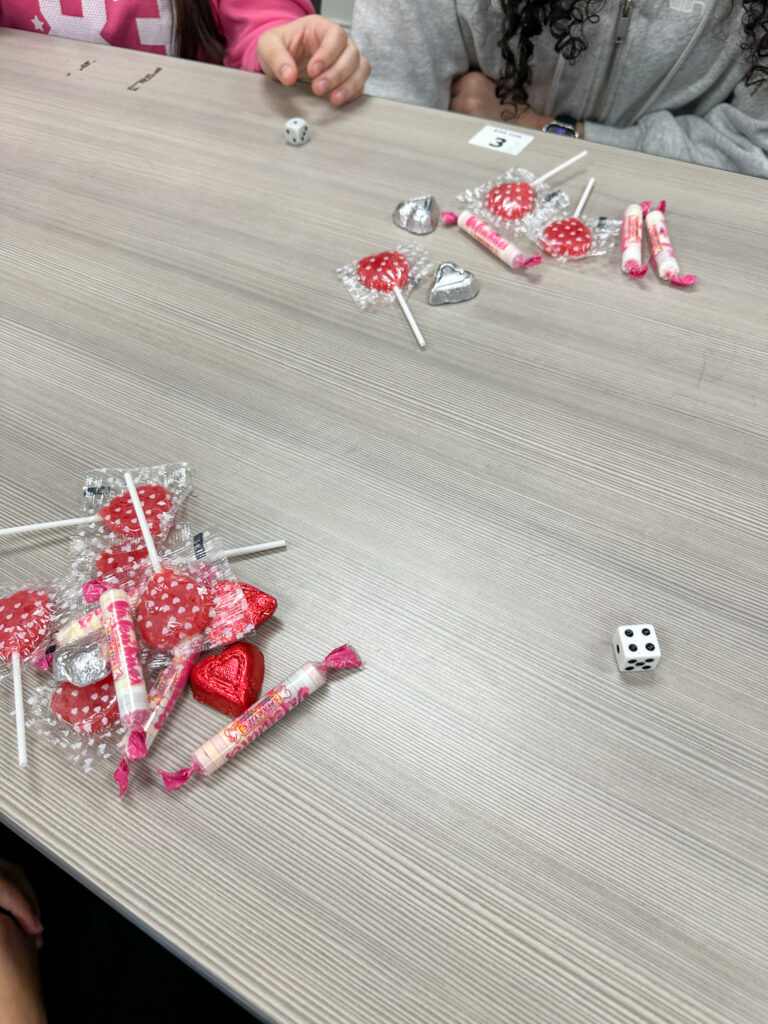 classroom single die roller and candy on table for Valentine's Day activity