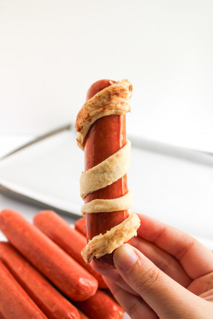 girl holds sausage wrapped in crescent dough