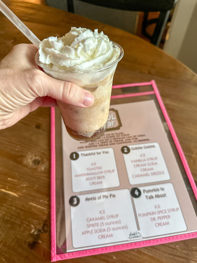 woman holds Thanksgiving dirty soda over menu on table