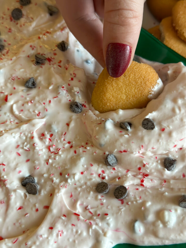 woman dips vanilla wafer into mint chocolate chip dip