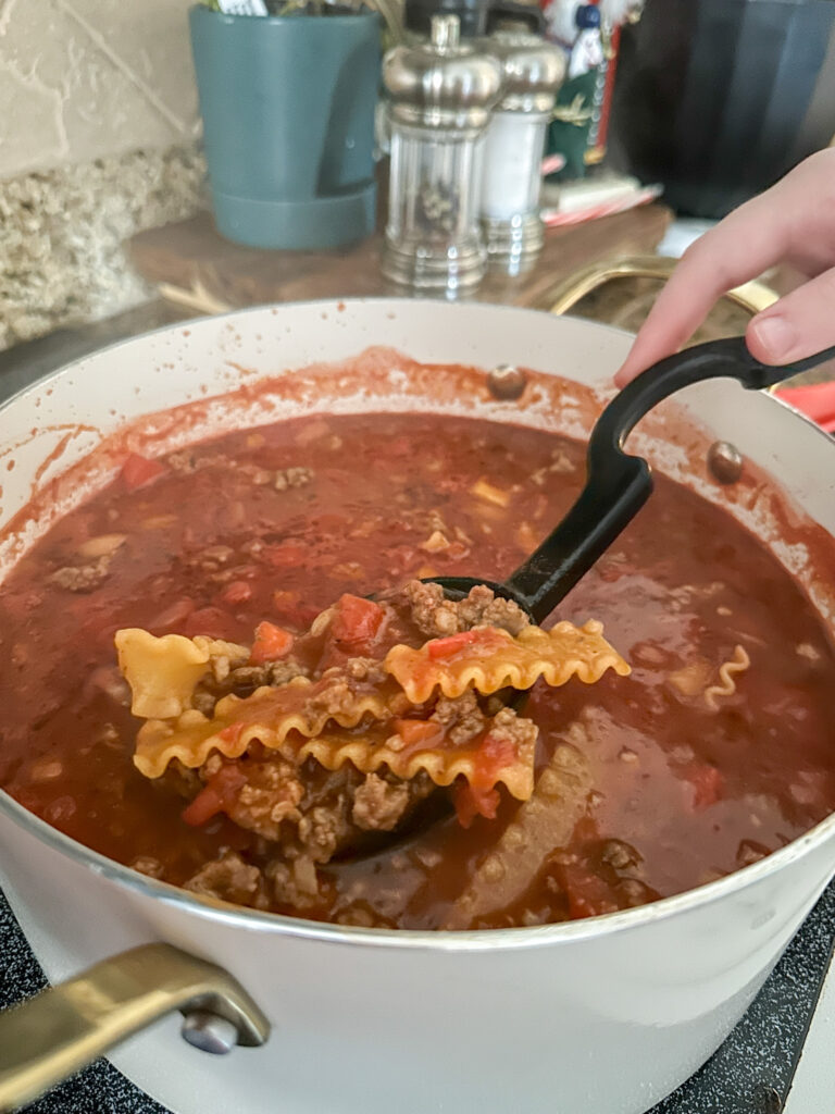 girl stirs one pot lasagna soup in a pot