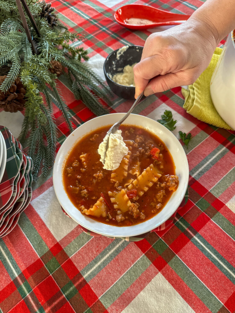 woman adds cheese to a one pot lasagna soup