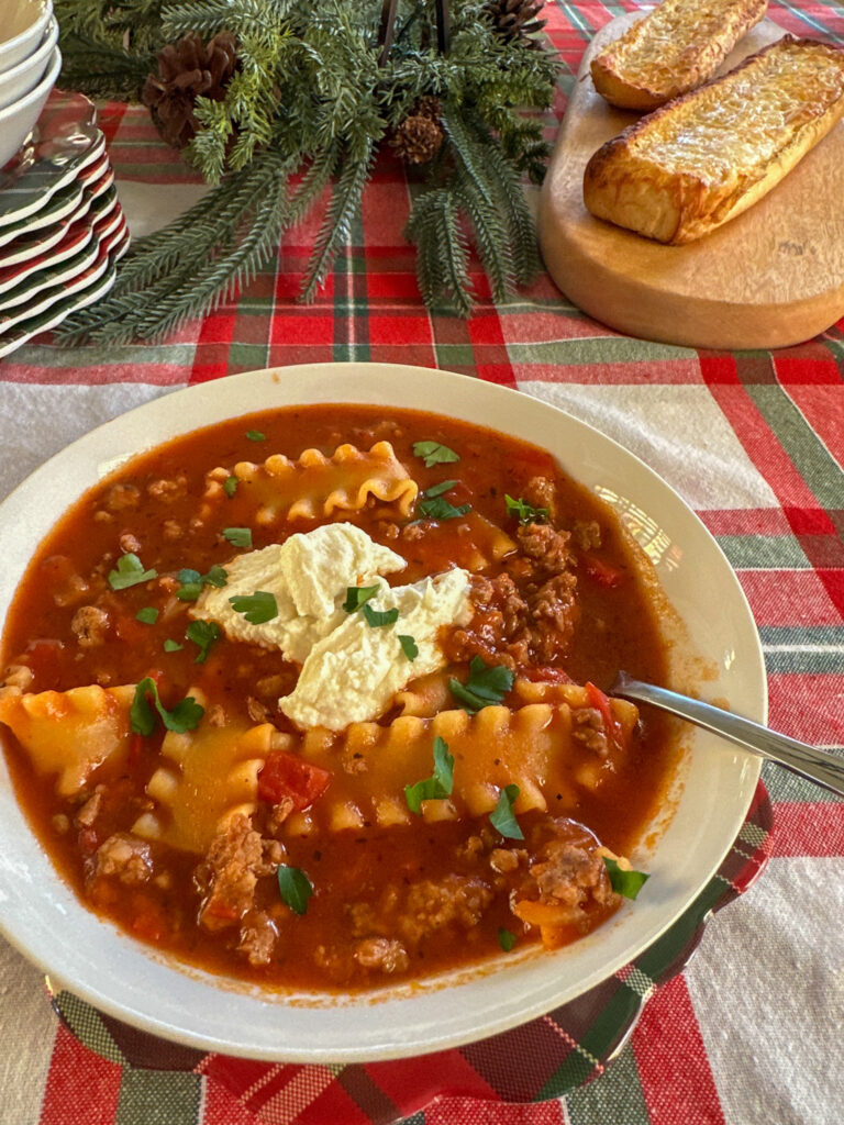 one pot lasagna soup in a white bowl on plaid tablecloth