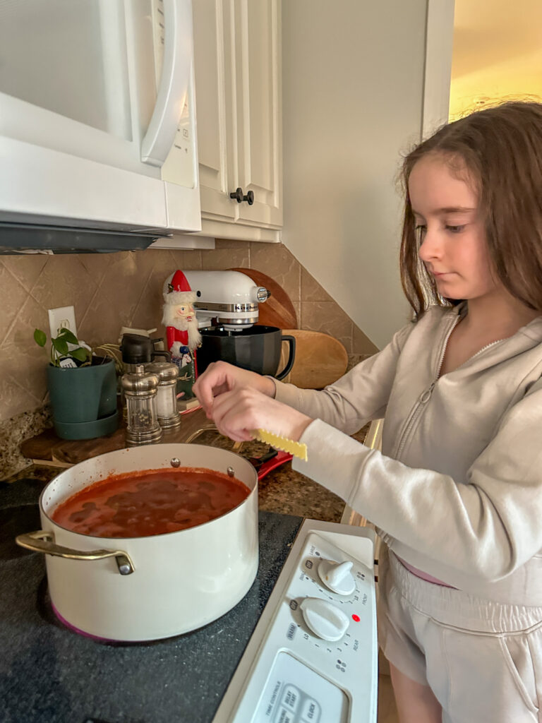 girl breaking noodles over pot