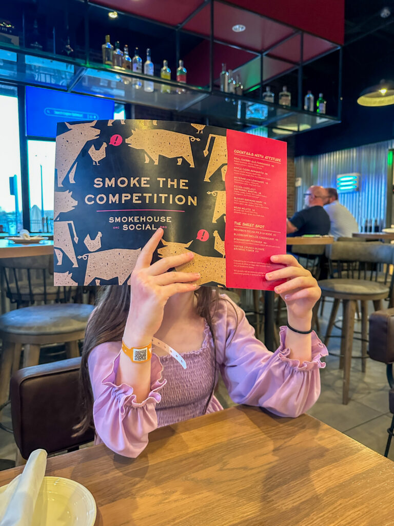little girl reading a menu at Smokehouse Social Restaurant at Okana Resort in Oklahoma City