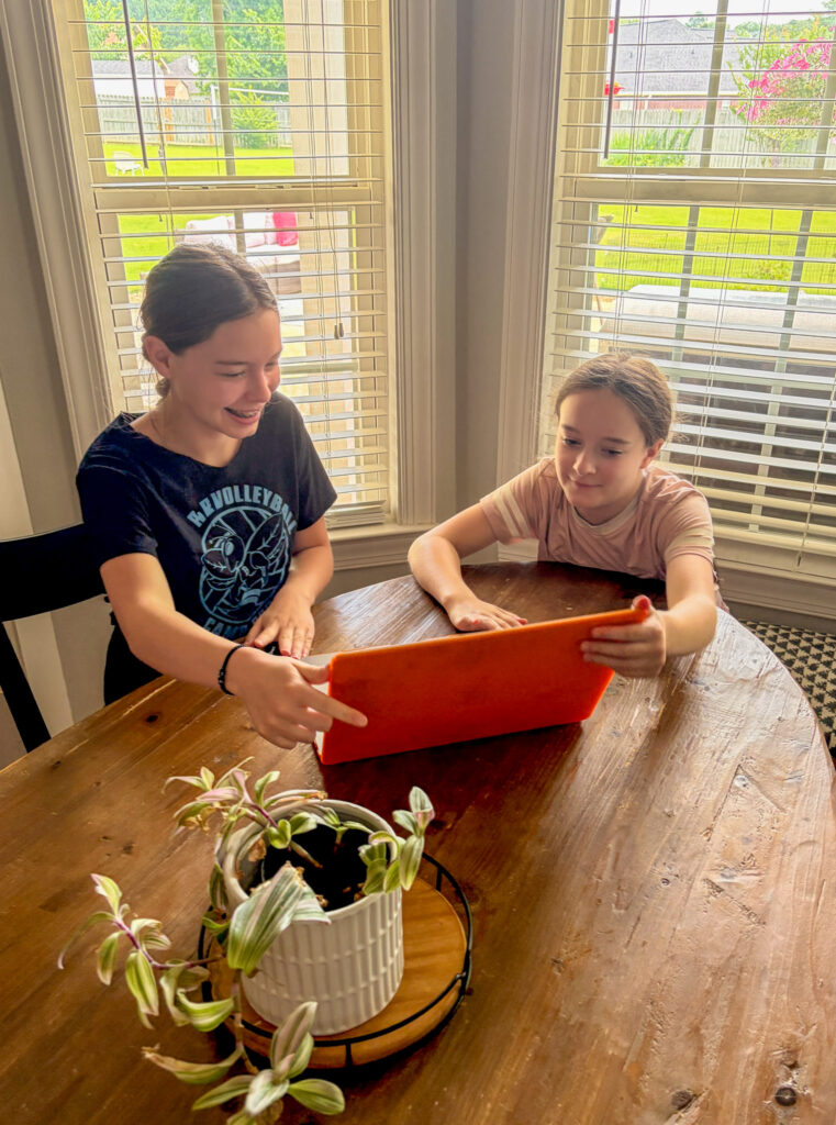 girls looking at laptop to find the Groupon Mystery Vacation reveal