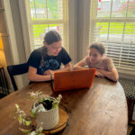 girls look at email from Groupon Mystery Vacation deal