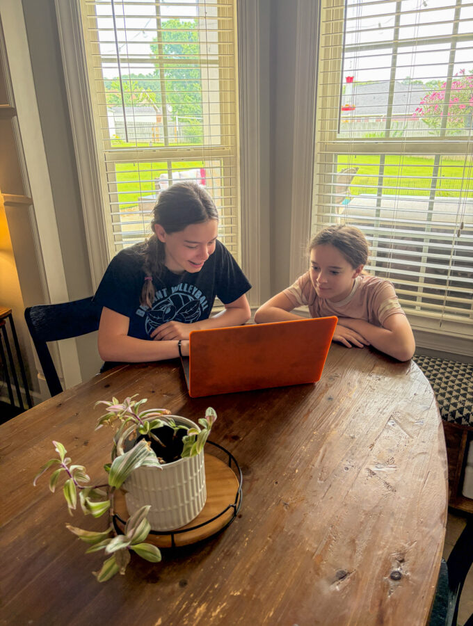 girls look at email from Groupon Mystery Vacation deal